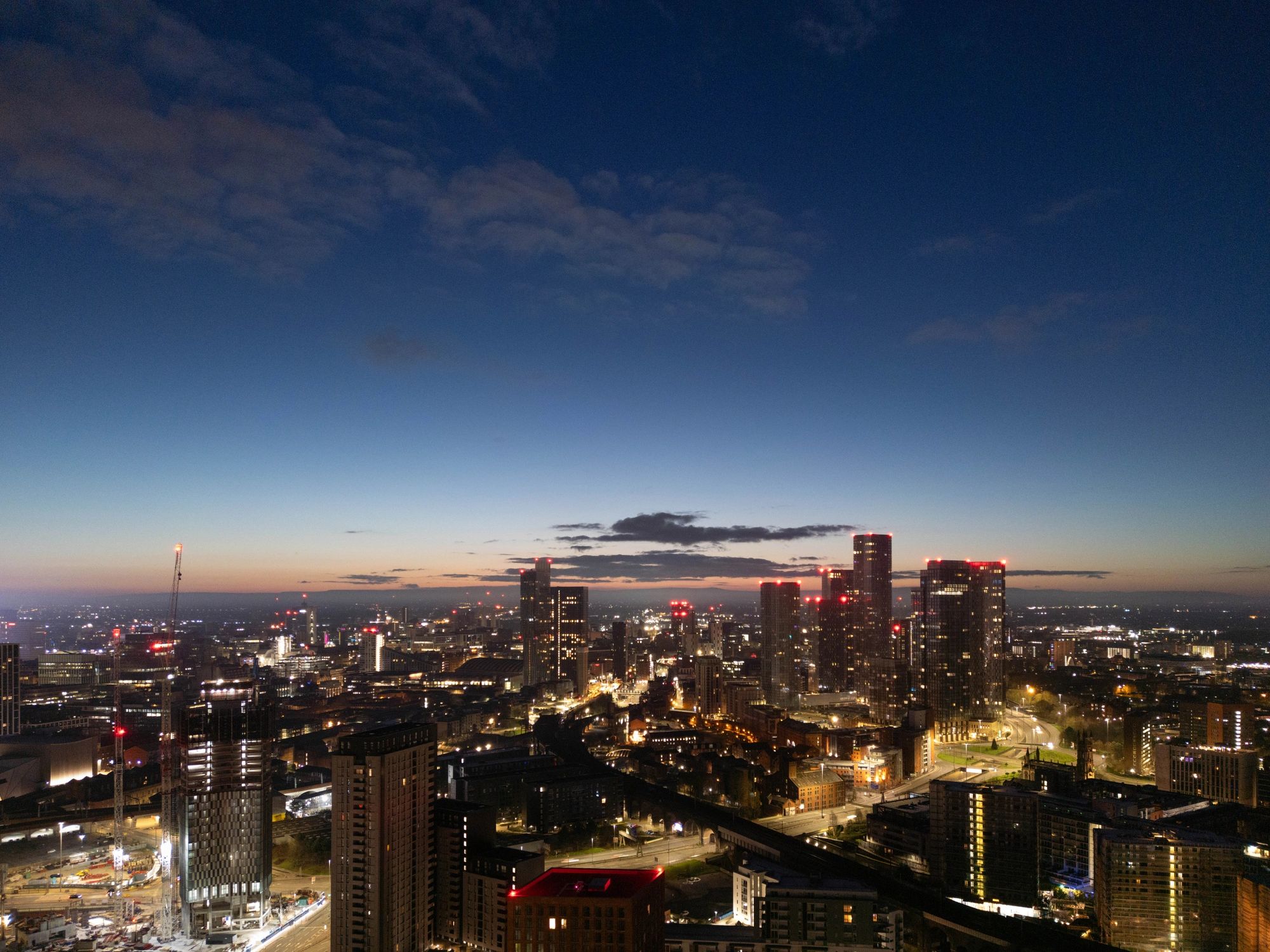 Manchester Cityscape at Sunrise Featuring Illuminated Skyscrapers and Suburban Landscape