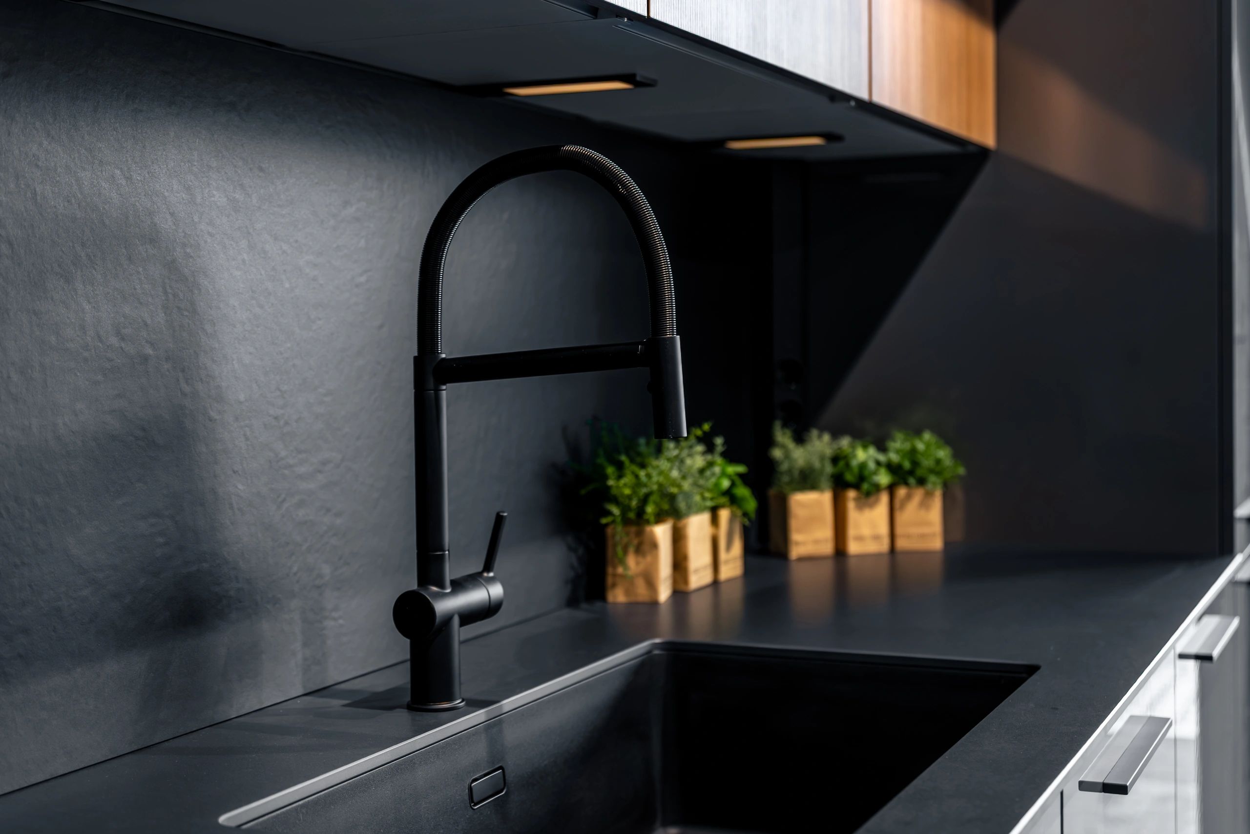 Elegant matte black faucet in dark kitchen. Premium interior design with minimalist furniture.